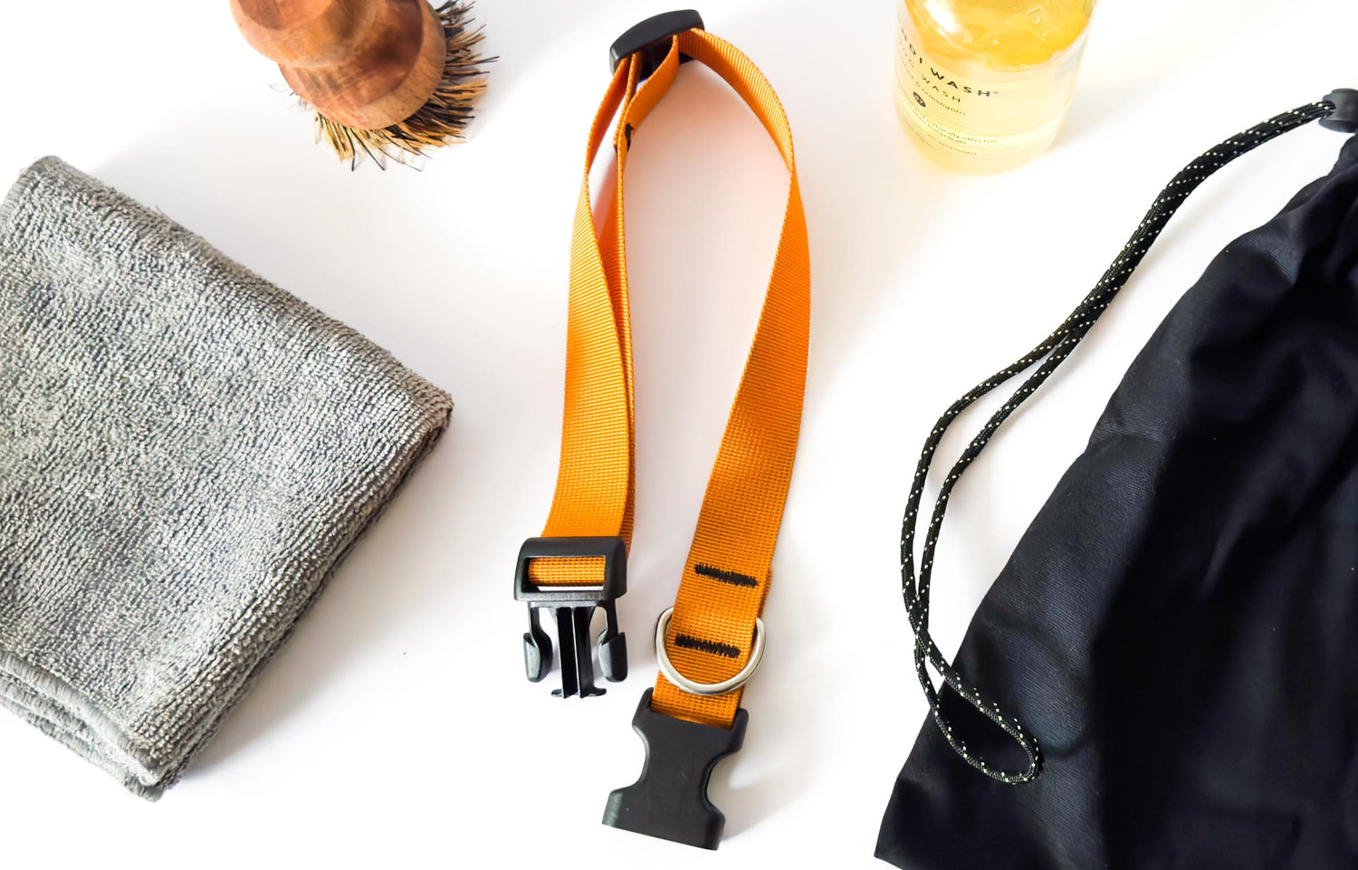 A clean dog collar laid out flat with dog shampoo, wash bag, brush, and cloth